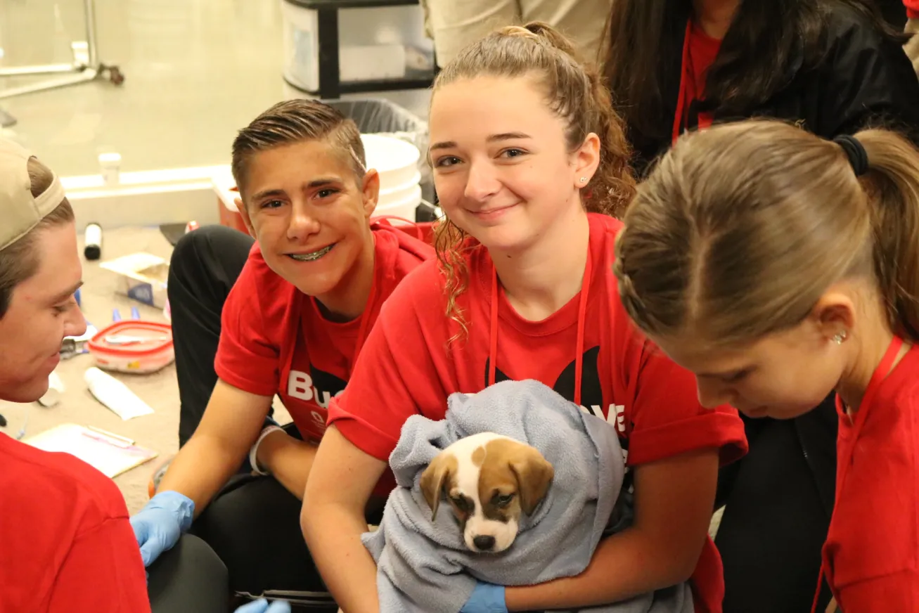 smiling students holding a dog