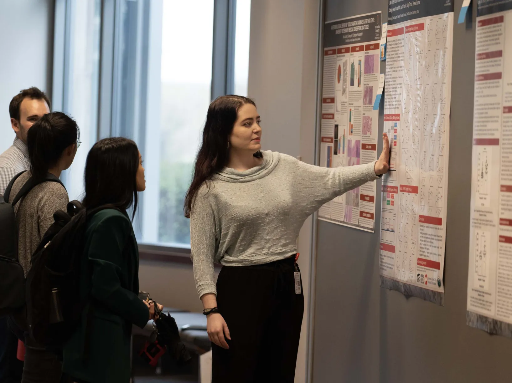 A woman explaining information on some posters to other students