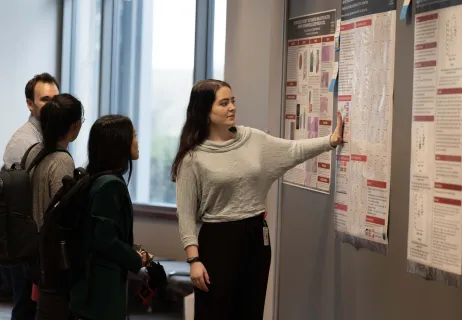 A woman explaining information on some posters to other students