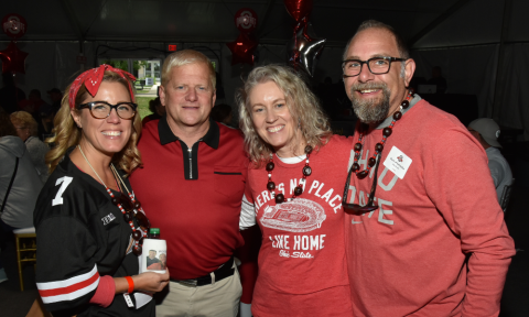 three alumni with dean rustin moore at homecoming wearing buckeye apparel