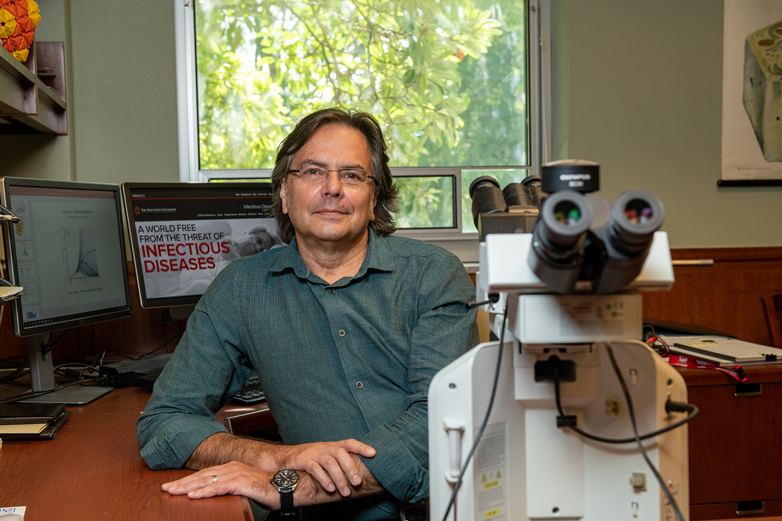 Dr. Michael Oglesbee pictured at his office desk with a microscope