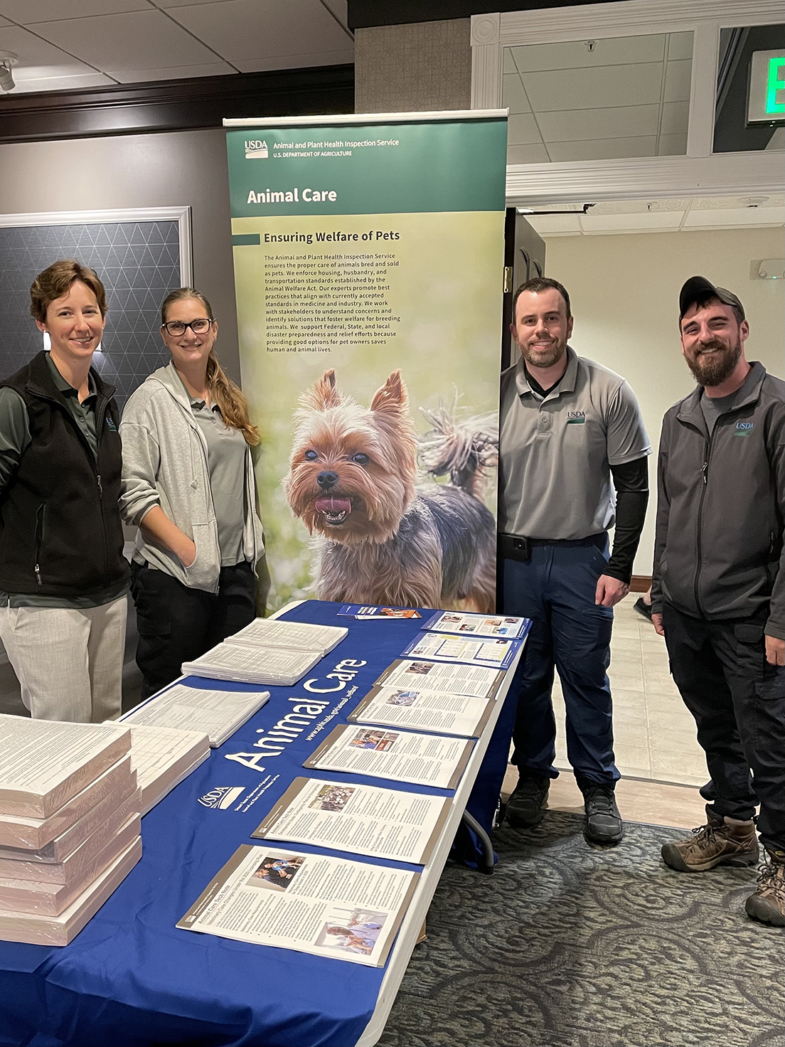 A group stands with Dr. Campiteli around an education booth at a dog breeders’ educational seminar