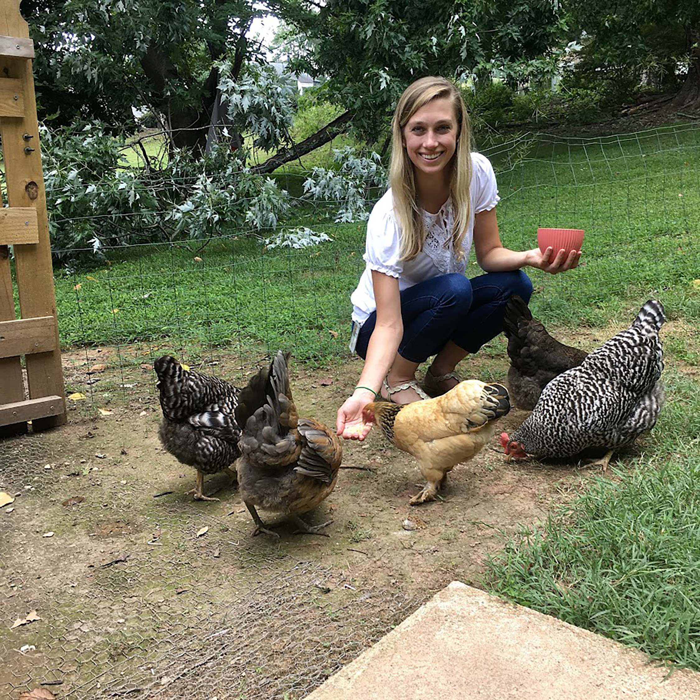 Sara Sklenka smiles and feeds chickens