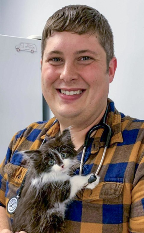 Headshot of Dr. Aaron Pospisil wearing a stethoscope and holding a kitten