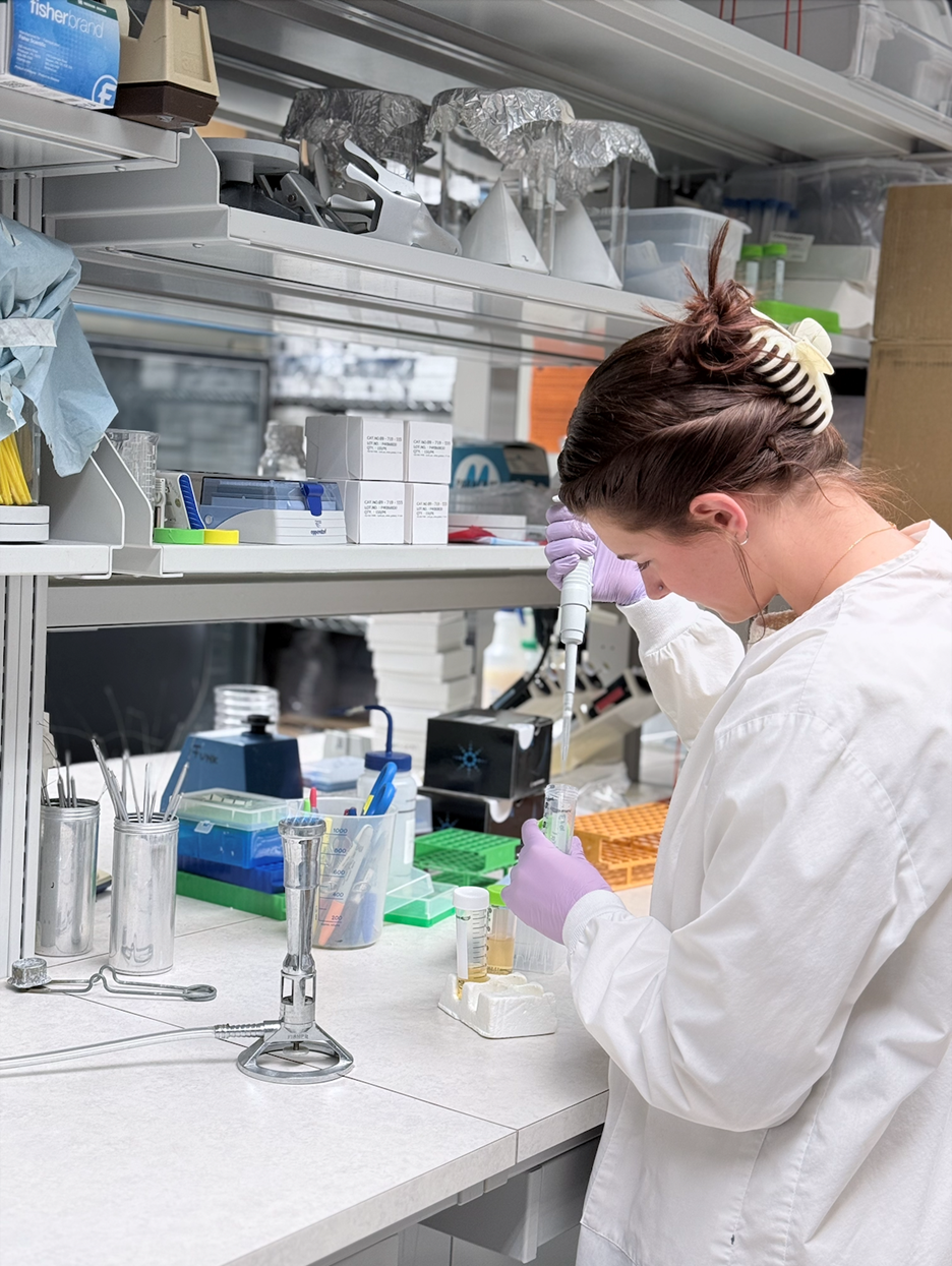 student researcher at bench in lab with pippette