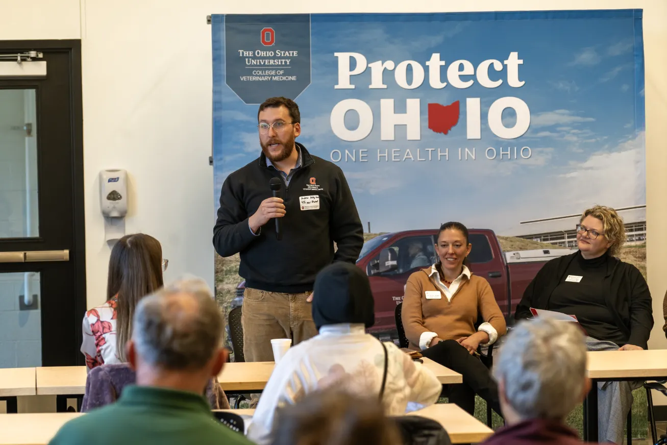 Veterinary student Drew King-Smith stands and speaks into microphone to audience
