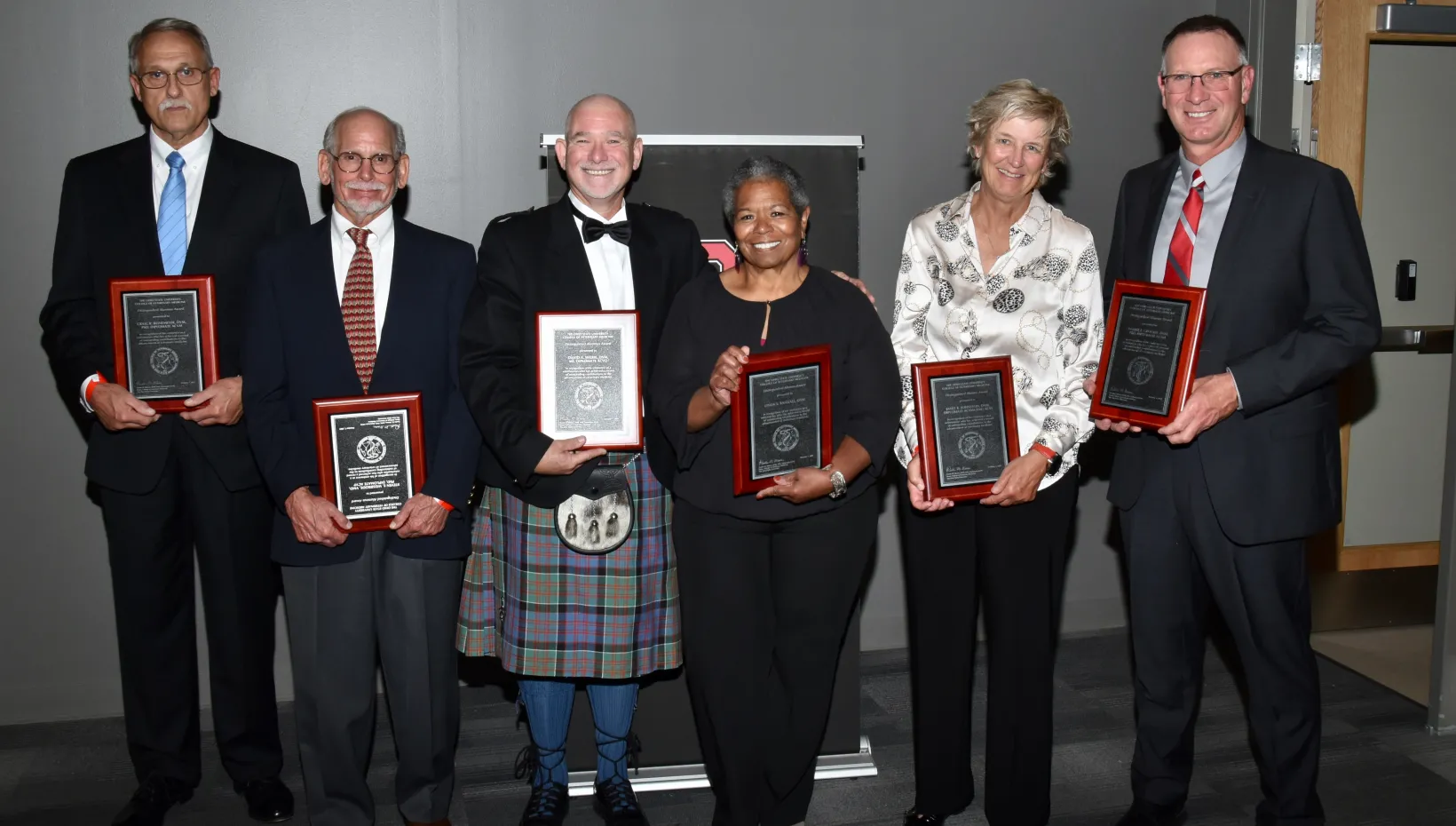 A group of people, each holding an award