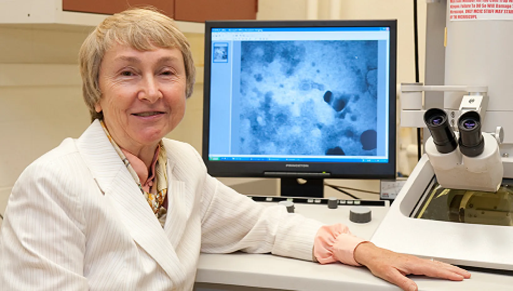 A vet posing in front of a microscope and slide