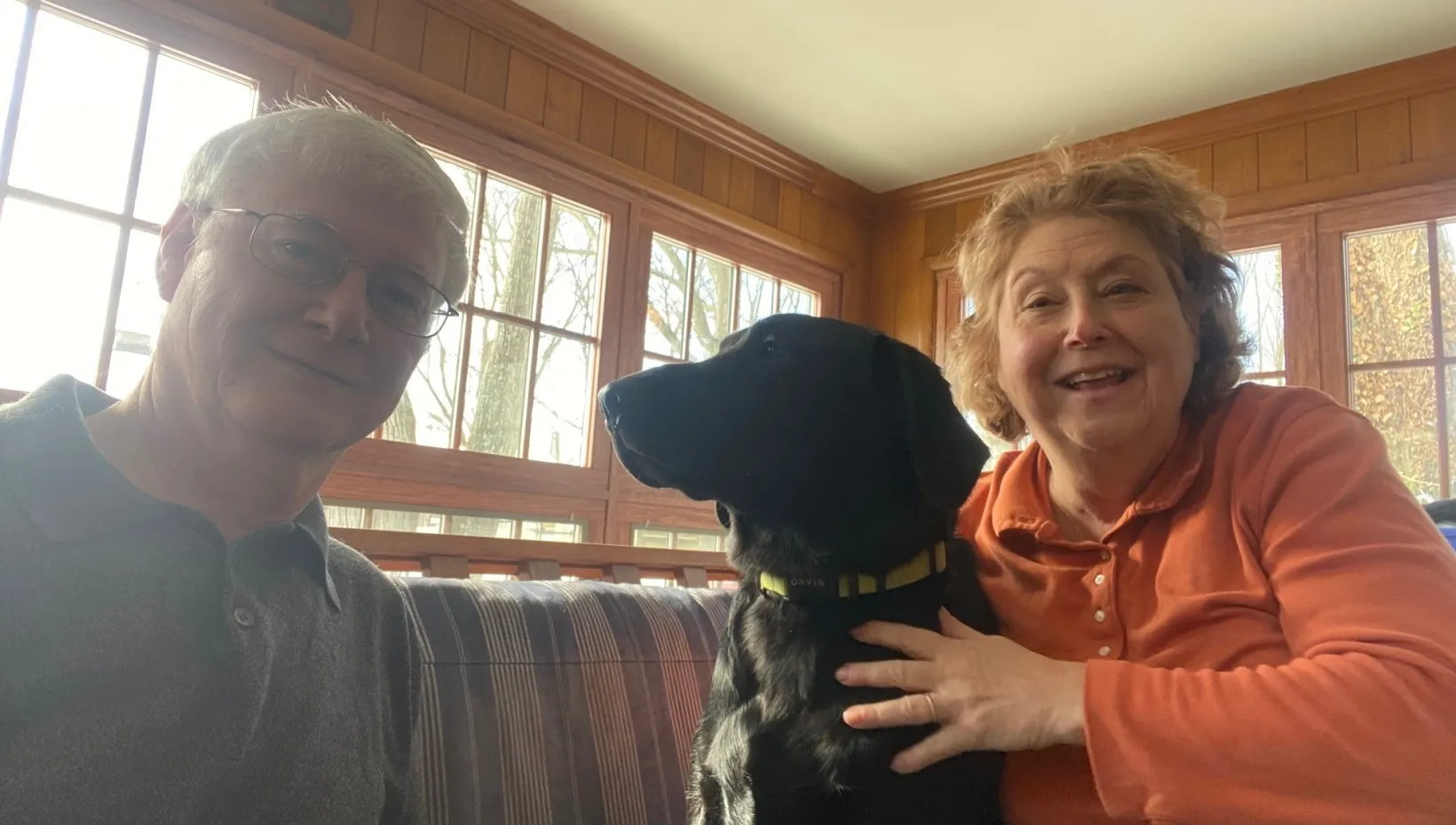 Two people and their dog sitting on a couch