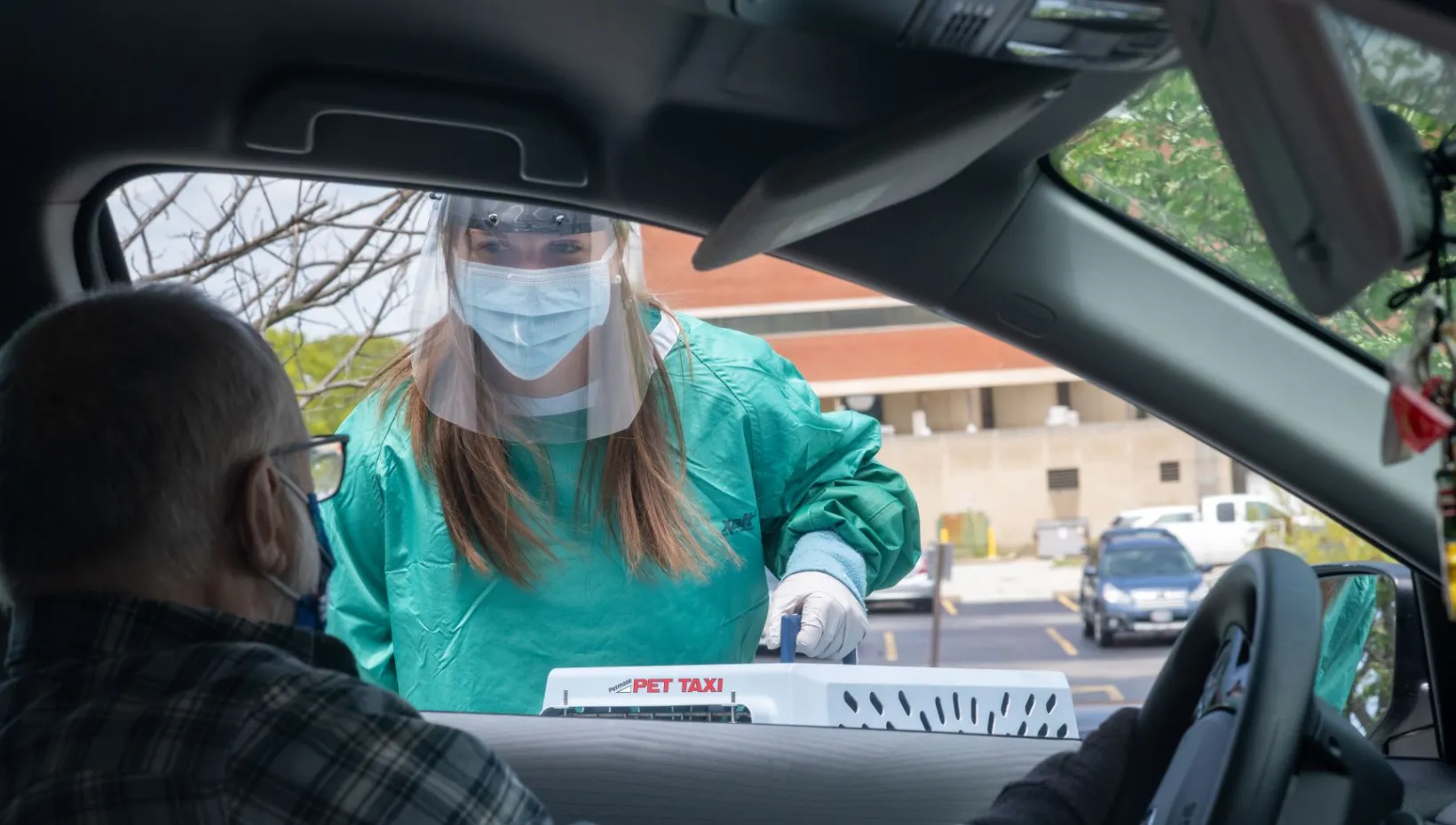 A vet bring a crated cat back to the owner in his car