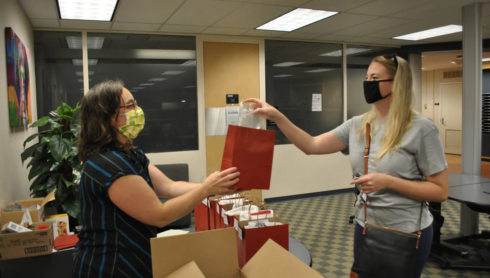 A woman handing another woman a gift bag