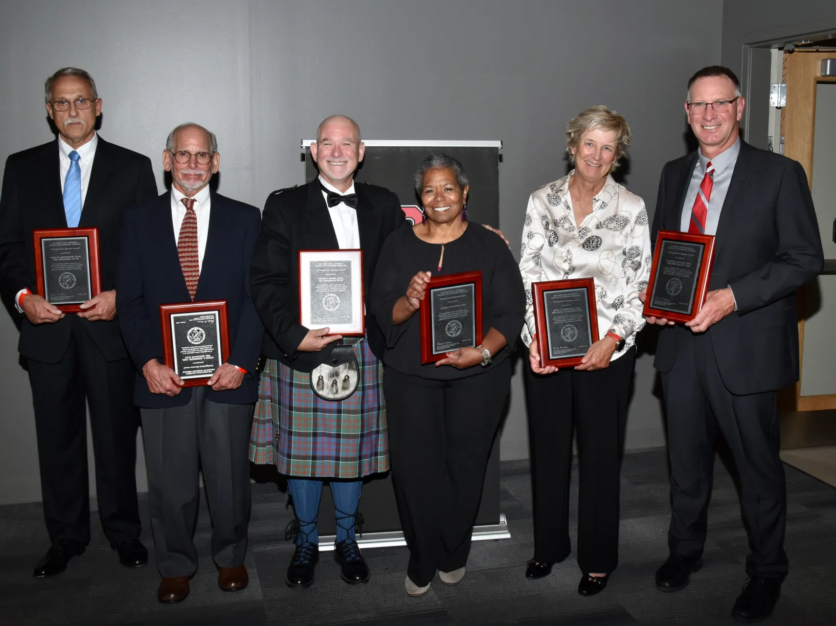 A group of people, each holding an award