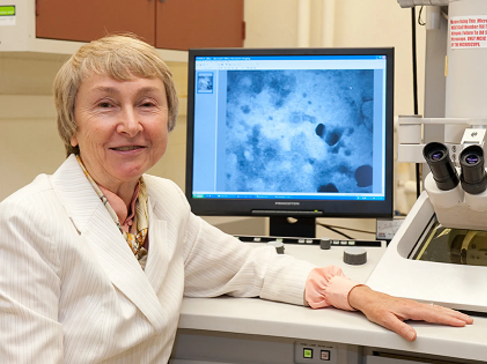 A vet posing in front of a microscope and slide