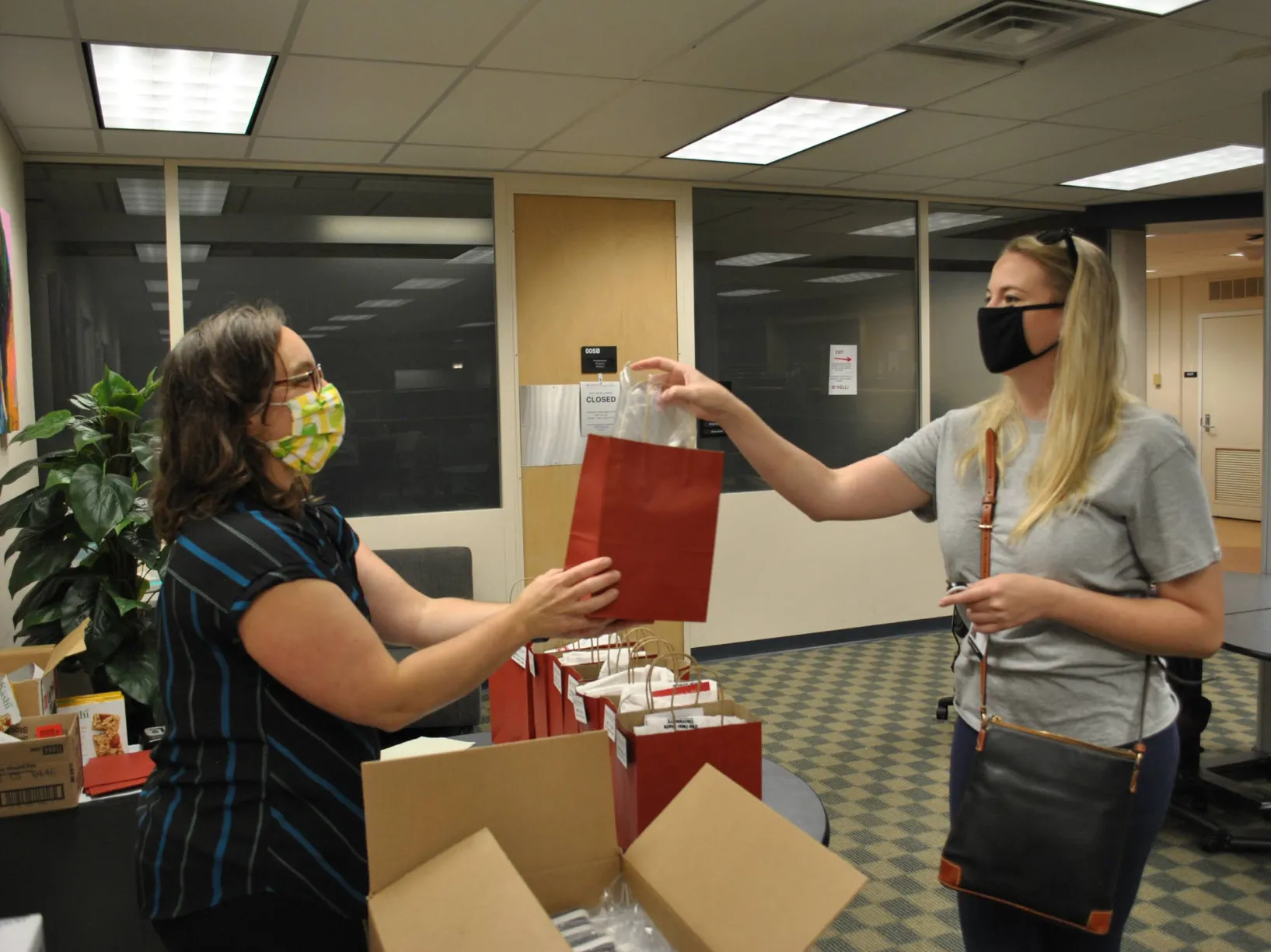 A woman handing another woman a gift bag