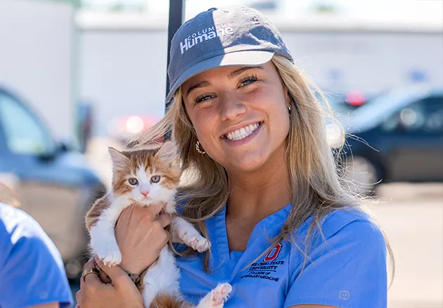 Veterinary Student at the Columbus Humane Vaccine Clinic smiling and holding a kitten