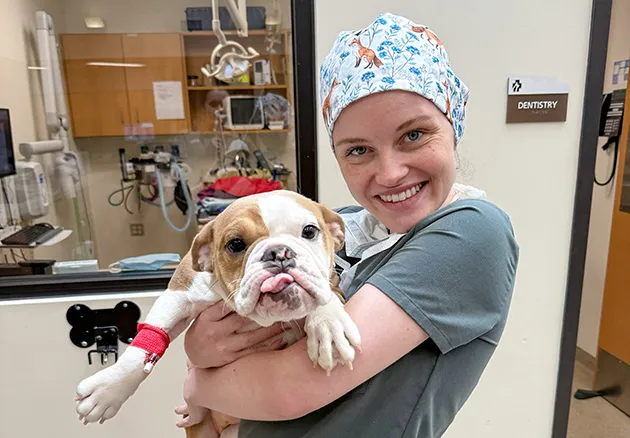 veterinary student holding dog and smiling 
