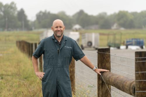 Dr. Greg Habing at Waterman Farm, standing near a fence with open field behind him