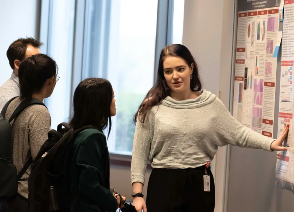 Student pointing to a poster, showing another student