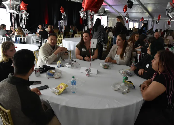 seven people sitting at a table networking