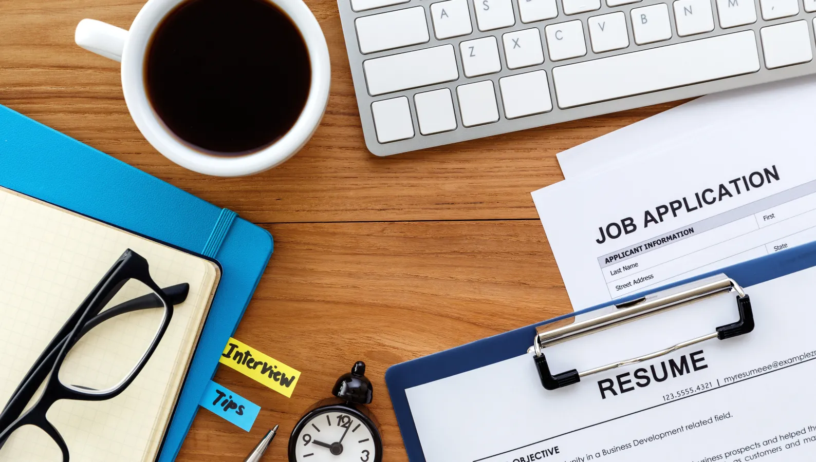 close up image of a desk with cup of coffee, computer key board and resume