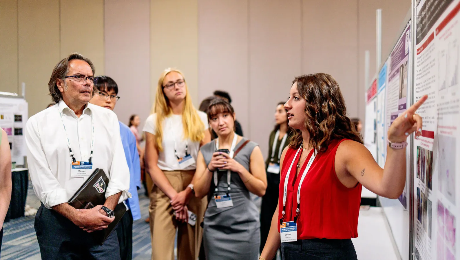 group of people watch as student presents poster