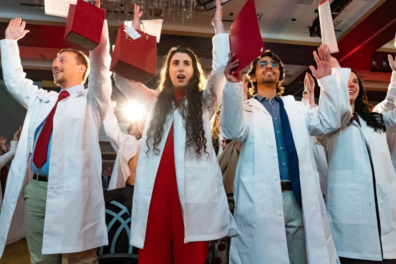 students at white coat ceremony making an H with their hands